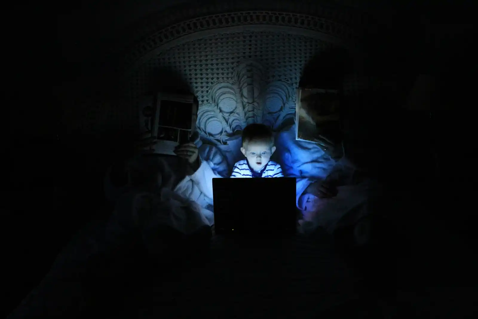 A child using a laptop in a darkened room