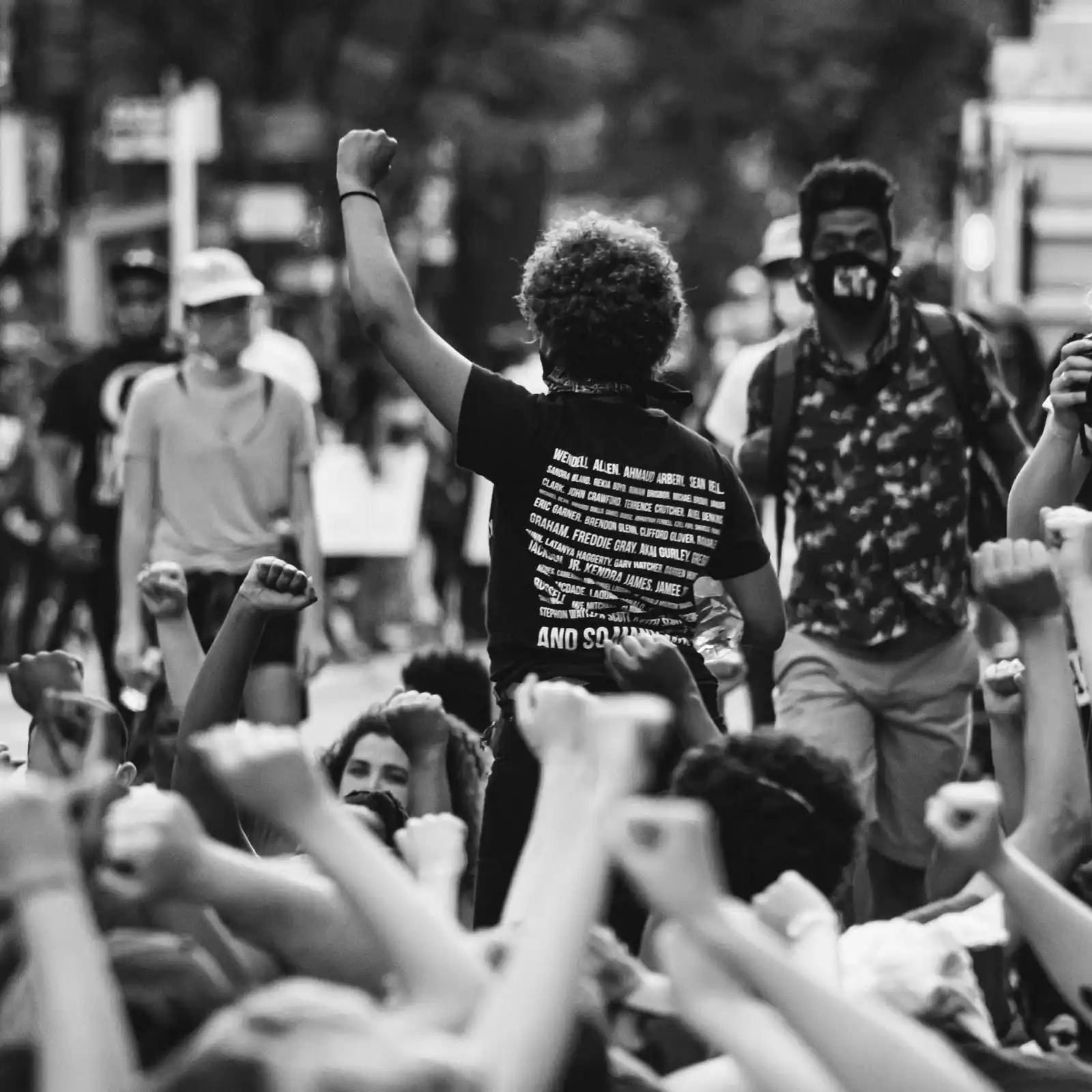Black-and-white photo of people raising their fists at a protest.